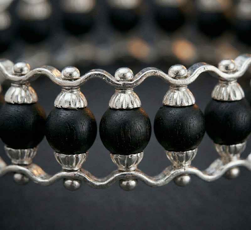 Close-up of a necklace with black beads and silver accents on a dark background