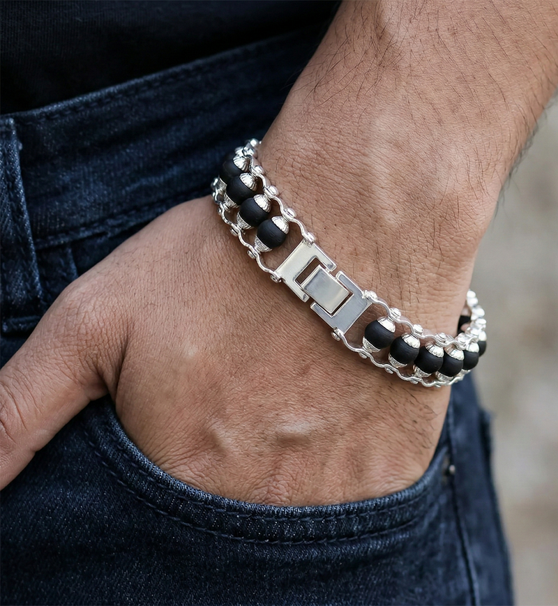 Close-up of a person wearing a silver and black beaded bracelet on a blurred background