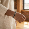 Close-up of a person's wrist wearing a bracelet with a blurred indoor background