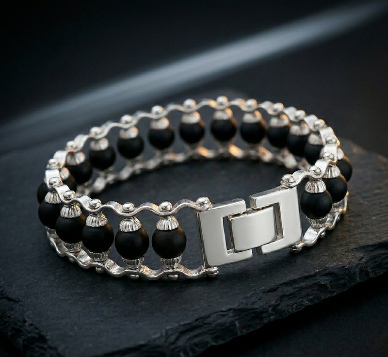 Black beaded bracelet with silver clasp on a dark surface