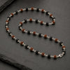 Necklace with black, brown, and silver beads on a dark surface