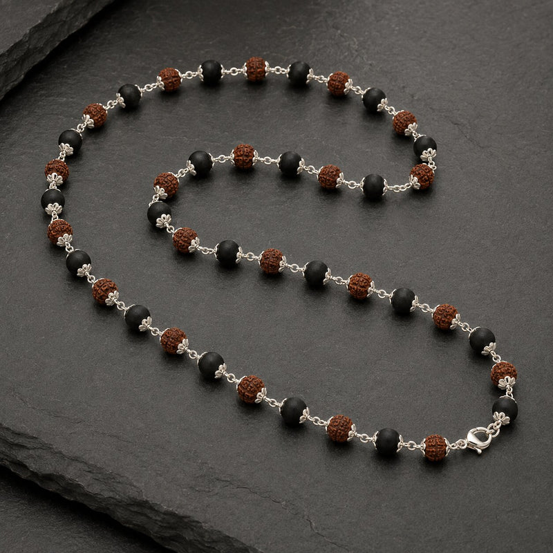 Necklace with black, brown, and silver beads on a dark surface