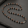 Necklace with black, brown, and silver beads on a dark surface