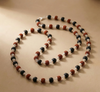 Necklace with black, red, and silver beads on a beige background