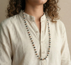 Person wearing a long beaded necklace with a neutral background
