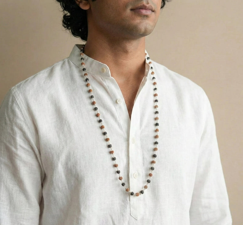 Man wearing a long beaded necklace with a plain background