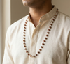 Person wearing a long beaded necklace with a neutral background